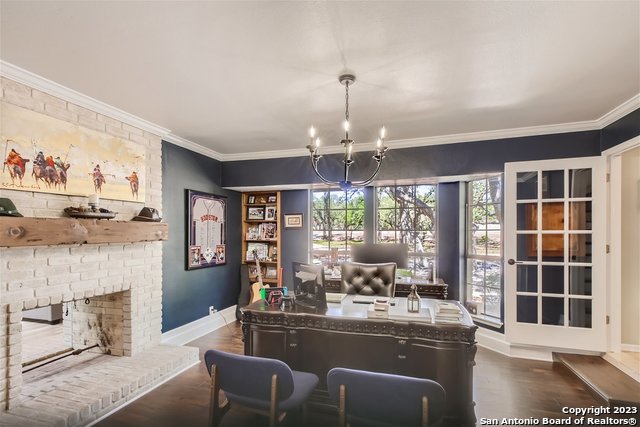 office space with dark hardwood / wood-style floors, crown molding, a chandelier, and a fireplace