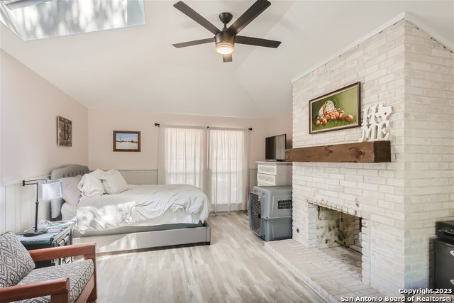 bedroom featuring ceiling fan, vaulted ceiling, and a fireplace