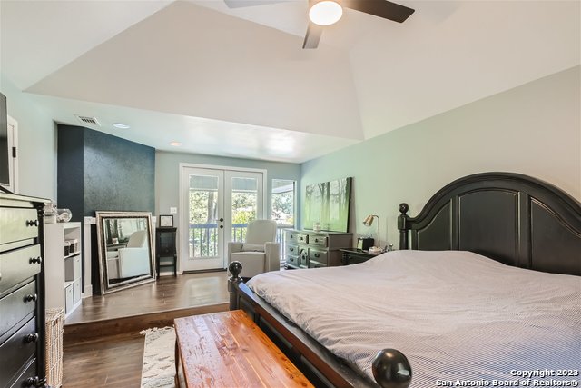 bedroom featuring ceiling fan, lofted ceiling, access to outside, wood-type flooring, and french doors