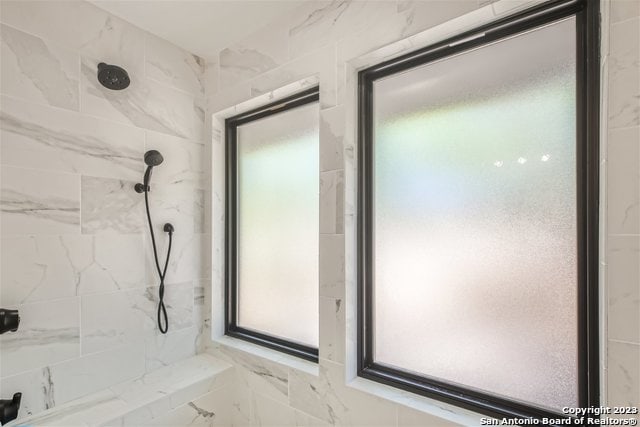 bathroom featuring a tile shower and a healthy amount of sunlight