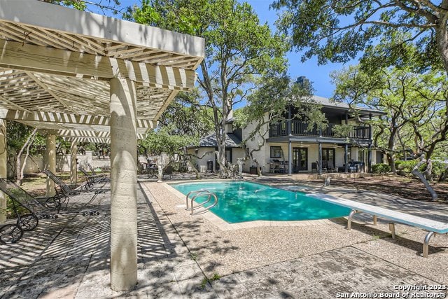 view of pool with a patio area, a diving board, and a pergola