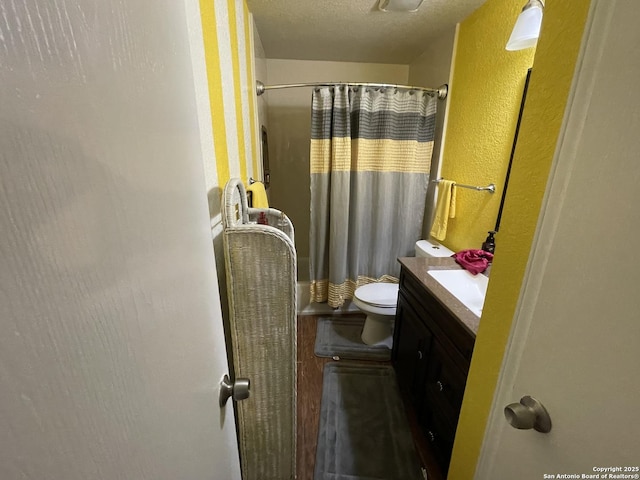 bathroom with toilet, vanity, walk in shower, and a textured ceiling