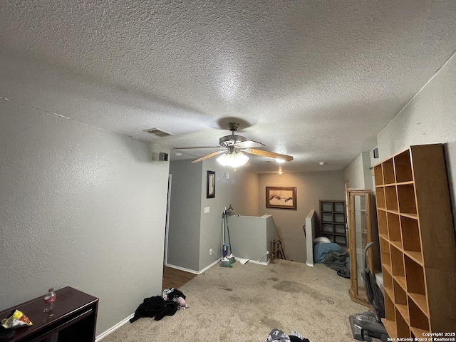 misc room featuring carpet floors, a textured ceiling, and ceiling fan