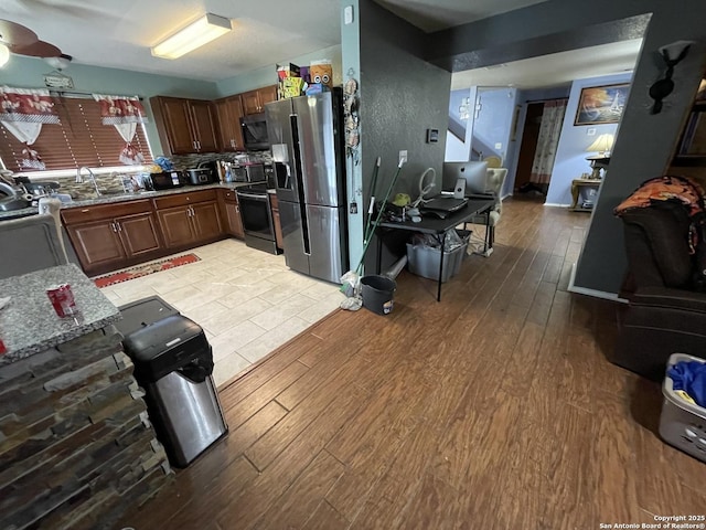 kitchen with backsplash, appliances with stainless steel finishes, sink, and light hardwood / wood-style floors