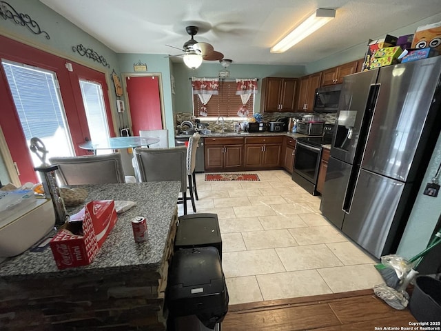 kitchen with light tile patterned floors, range with electric stovetop, stainless steel fridge, ceiling fan, and sink