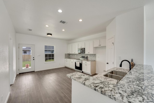 kitchen with kitchen peninsula, sink, white cabinetry, stainless steel appliances, and light stone counters