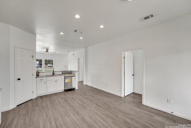 kitchen featuring white cabinets, light stone countertops, stainless steel dishwasher, light hardwood / wood-style flooring, and sink