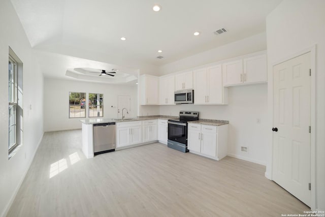 kitchen with ceiling fan, stainless steel appliances, a raised ceiling, and white cabinets