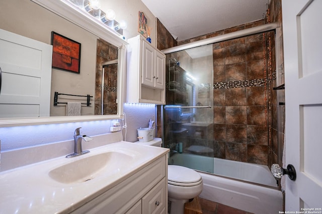 full bathroom with enclosed tub / shower combo, vanity, and toilet