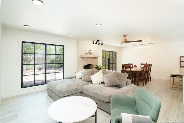 living room featuring a brick fireplace, light hardwood / wood-style flooring, and ceiling fan