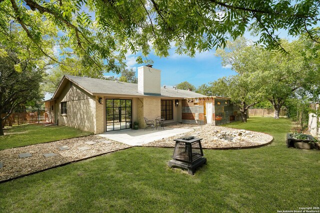 back of property with a fire pit, a patio, and a yard