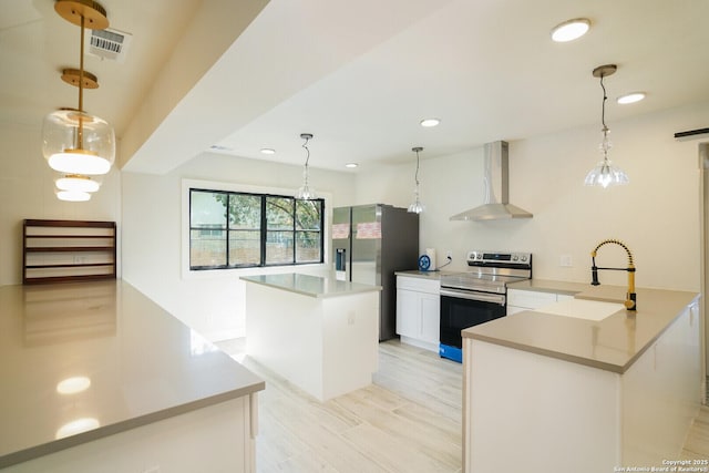 kitchen with decorative light fixtures, wall chimney exhaust hood, and stainless steel appliances