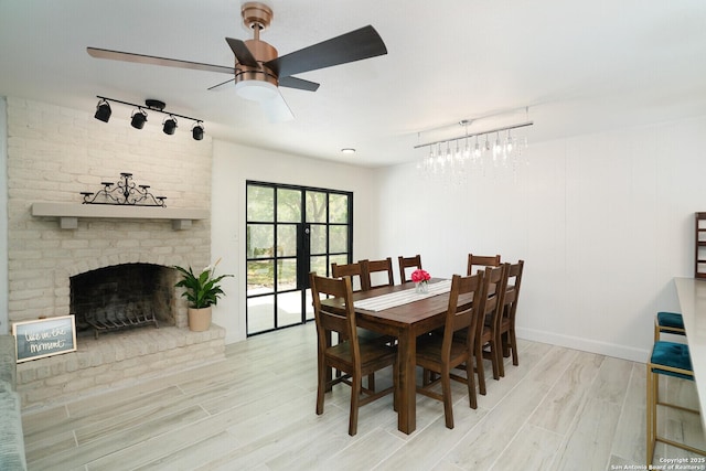 dining space with ceiling fan, light wood-type flooring, and a fireplace