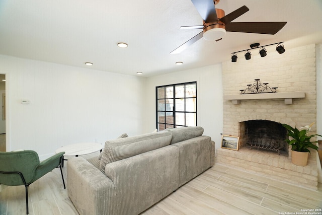 living room with ceiling fan, light wood-type flooring, and a fireplace