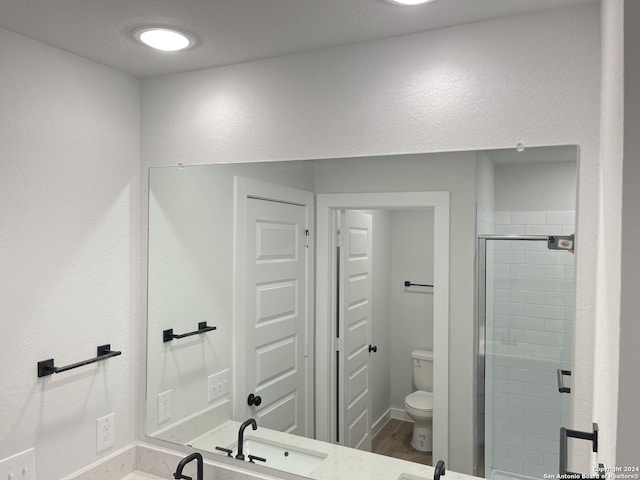 bathroom with toilet, an enclosed shower, and sink