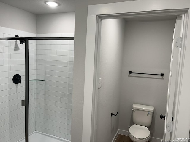 bathroom featuring a shower with shower door and toilet