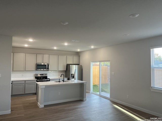 kitchen with gray cabinets, sink, hardwood / wood-style flooring, a kitchen island with sink, and stainless steel appliances