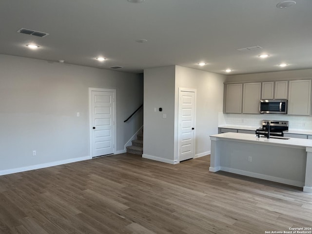 kitchen featuring appliances with stainless steel finishes, tasteful backsplash, sink, gray cabinets, and light hardwood / wood-style flooring