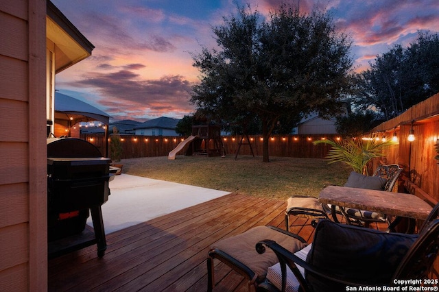 deck at dusk with a playground and a yard