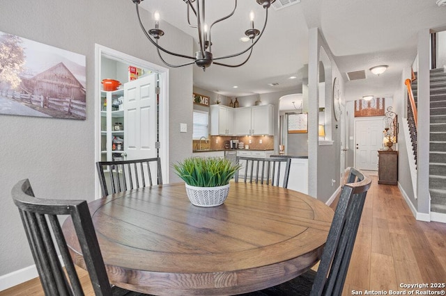 dining space with light hardwood / wood-style floors, sink, and a notable chandelier