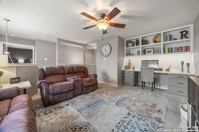 living room featuring light carpet, ceiling fan, built in desk, and a textured ceiling