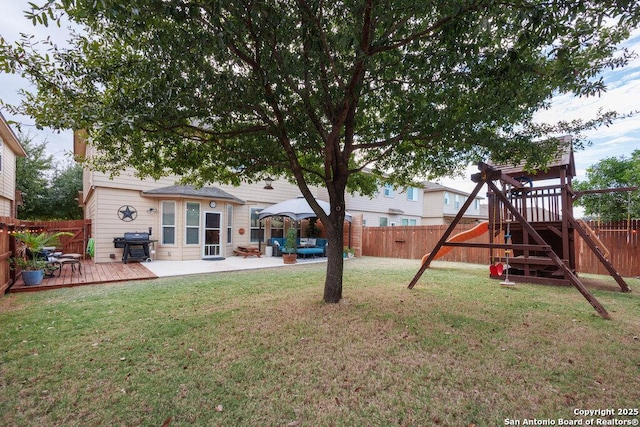 view of yard with a deck, a patio, and a playground