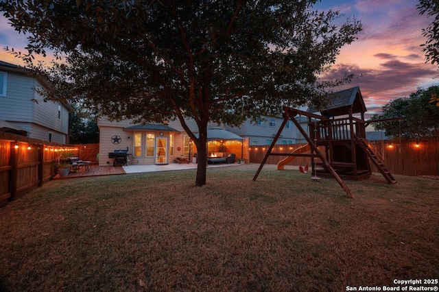 playground at dusk with a yard, an outbuilding, and a patio