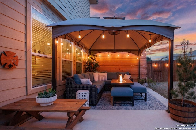 patio terrace at dusk featuring a gazebo and an outdoor living space with a fire pit