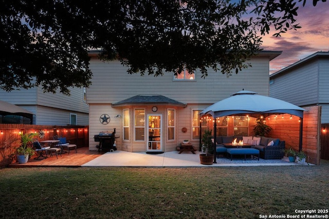 back house at dusk with a deck, a gazebo, a yard, and an outdoor hangout area