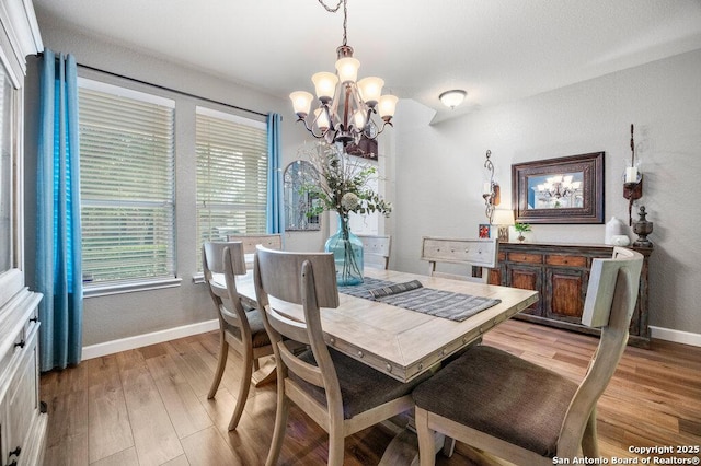 dining area featuring light wood-type flooring and an inviting chandelier