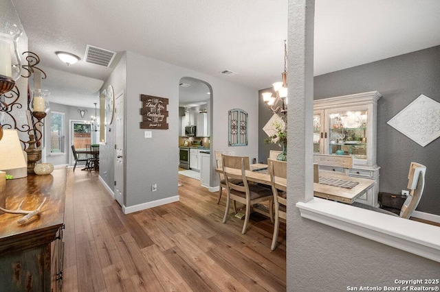 dining room with a textured ceiling, light hardwood / wood-style flooring, and a chandelier