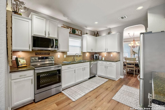 kitchen featuring white cabinets, backsplash, stainless steel appliances, and light hardwood / wood-style flooring