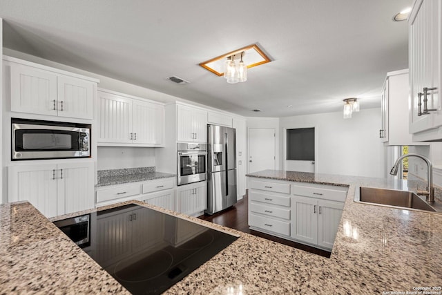 kitchen featuring white cabinets, appliances with stainless steel finishes, sink, and light stone counters