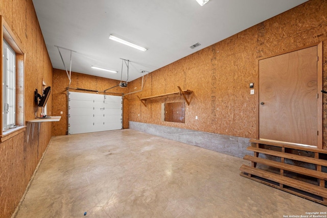 garage featuring a garage door opener and wooden walls