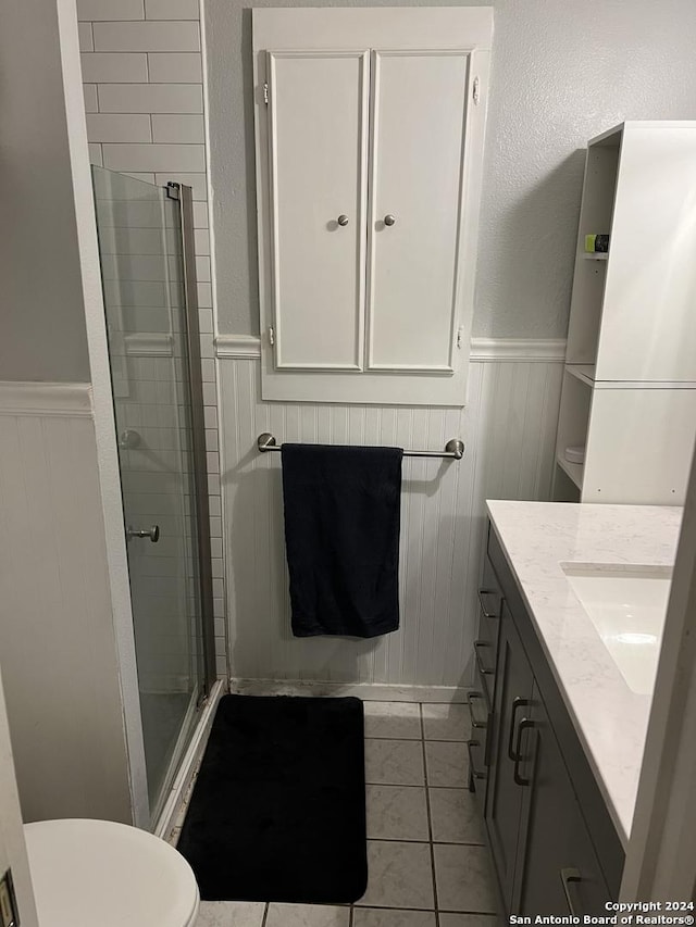 bathroom with vanity, toilet, tile patterned flooring, and a shower with door