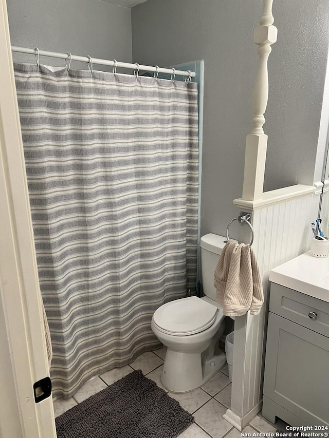 bathroom featuring toilet, a shower with curtain, tile patterned floors, and vanity