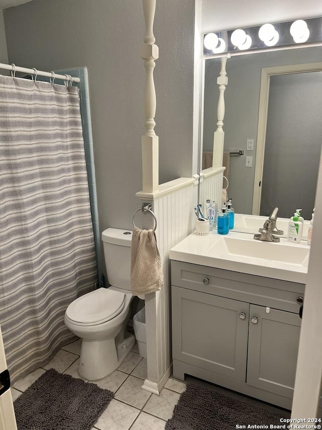 bathroom with toilet, tile patterned flooring, walk in shower, and vanity