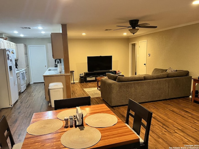 dining space featuring ceiling fan, ornamental molding, hardwood / wood-style floors, and sink