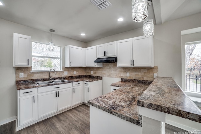 kitchen with light hardwood / wood-style floors, kitchen peninsula, sink, hanging light fixtures, and white cabinets