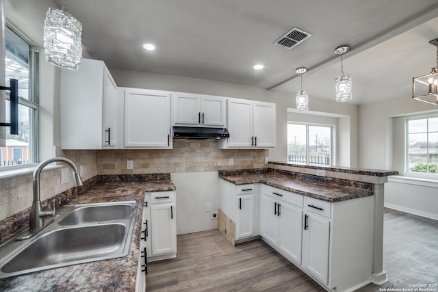 kitchen featuring an inviting chandelier, backsplash, pendant lighting, white cabinets, and sink