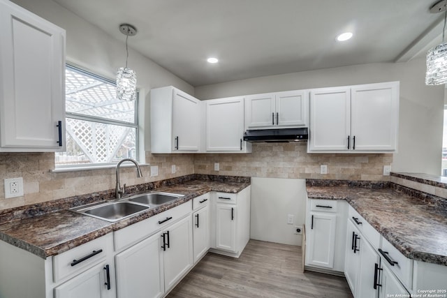 kitchen with decorative light fixtures, white cabinets, sink, and light hardwood / wood-style flooring