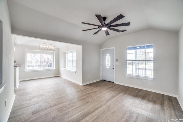 entrance foyer featuring ceiling fan with notable chandelier, light hardwood / wood-style floors, plenty of natural light, and lofted ceiling