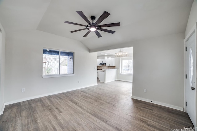 unfurnished living room featuring ceiling fan with notable chandelier, hardwood / wood-style floors, and vaulted ceiling