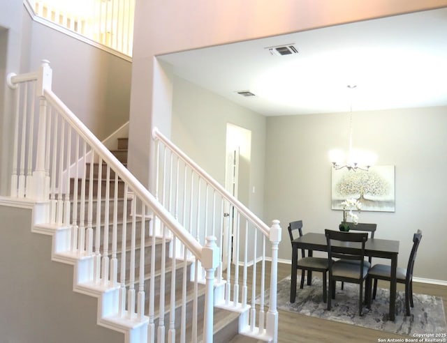 stairs with wood-type flooring and a chandelier