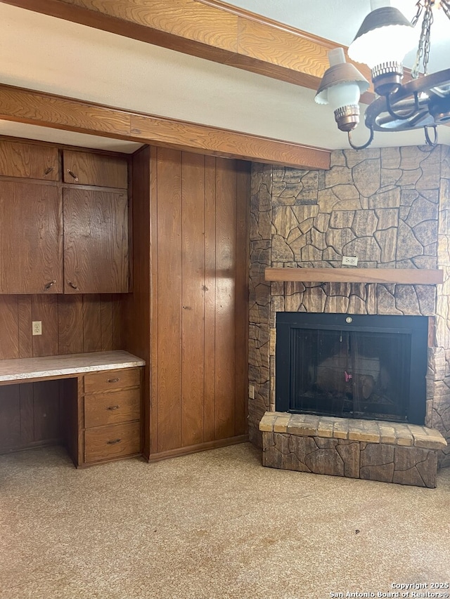 unfurnished living room featuring wood walls, a stone fireplace, and beamed ceiling