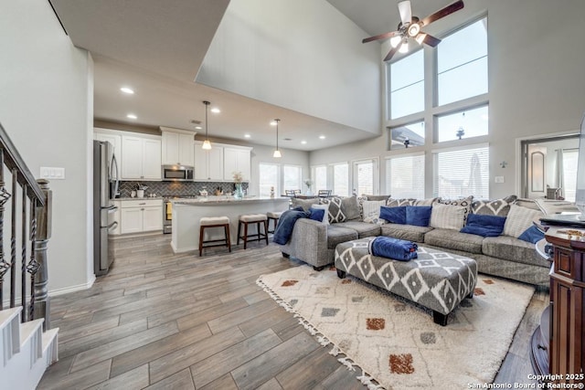 living room featuring ceiling fan and a high ceiling