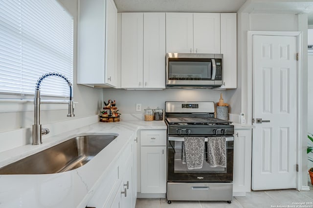 kitchen with light stone countertops, sink, white cabinetry, and appliances with stainless steel finishes