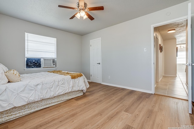 bedroom with a textured ceiling, ceiling fan, and light hardwood / wood-style flooring