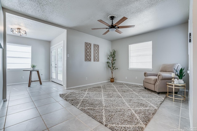 living area featuring ceiling fan, french doors, light tile patterned flooring, and a textured ceiling