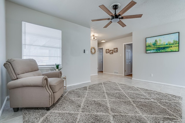 sitting room featuring ceiling fan, light tile patterned flooring, and a textured ceiling